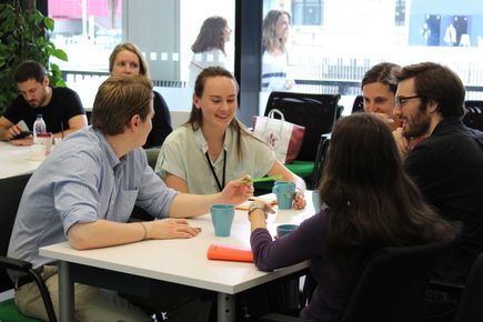 Group of students sitting around a table discussing things.