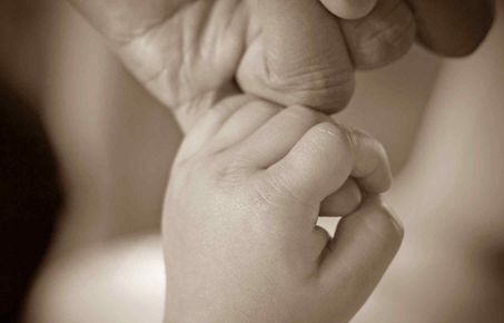 Baby holding adult finger