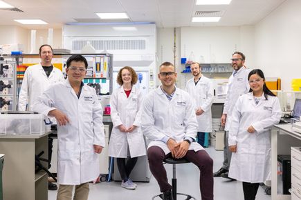 A group of people in lab coats posing for a photo in a lab