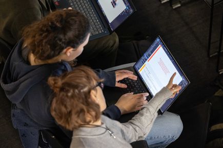 Bird's eye view of two students in the Dyson School of Engineering, working on one laptop together.