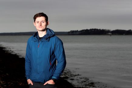 Portrait of Ciaran Dowds, one of the Entrepreneurs' Pledgers, against a backdrop of open water