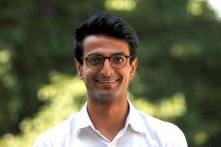 Portrait of Shrawan Patel, one of the Entrepreneur's Pledgers, smiling against a background of green leaves