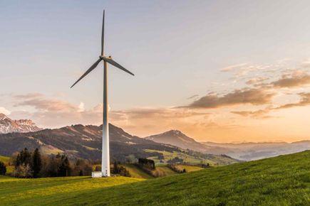 Wind turbine in mountainous agricultural terrain at sunset