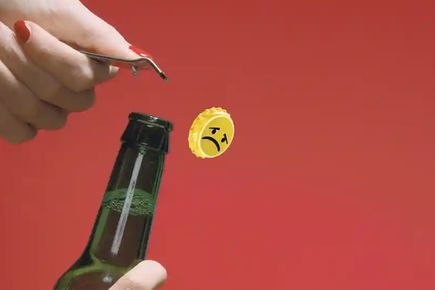 A picture of a beer bottle with a smiley face top being opened. Image by Observer Design
