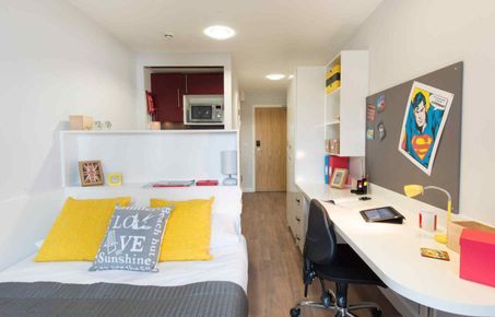 Image of halls of residence room with bed and desk