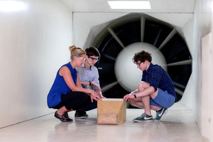 Students looking into a box in front of a large fan