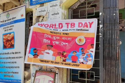 A public information poster for World TB day hangs in front of a shop