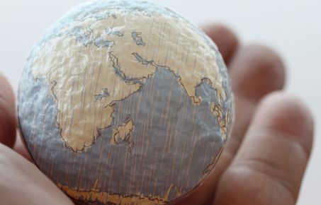 A small globe held in a hand