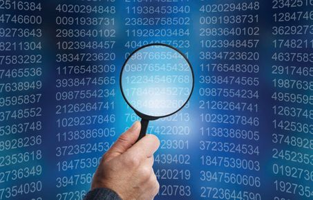 A magnifying glass inspects computer code