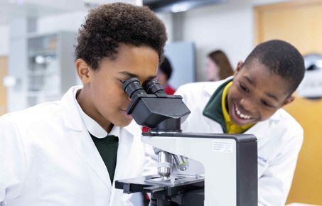 Two students looking through a microscope