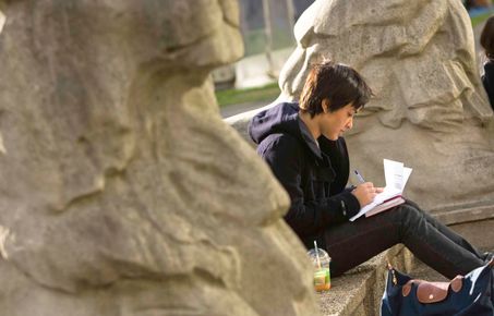 A student next to the stone lions at Imperial
