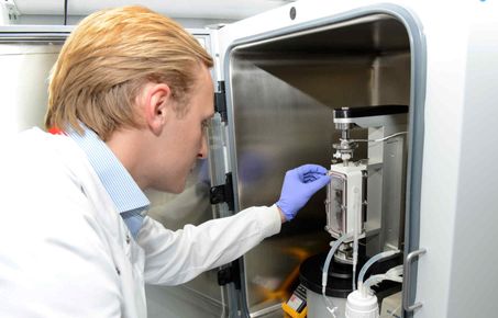 researcher leans in to use equipment in cabinet