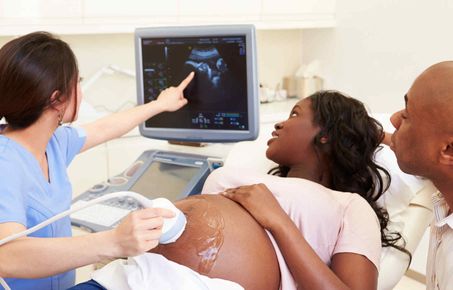 Couple look at ultrasound image of baby with nurse