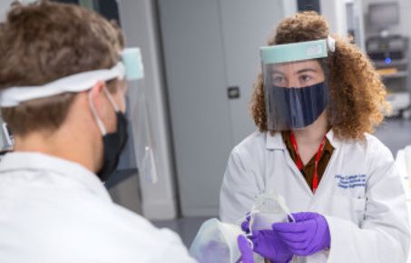 Researchers wear PPE and hold customisable face masks