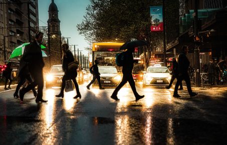 People crossing a busy road in the rain
