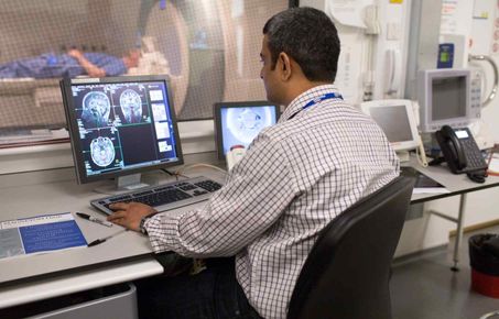 Man sitting at computer looking at brain scans