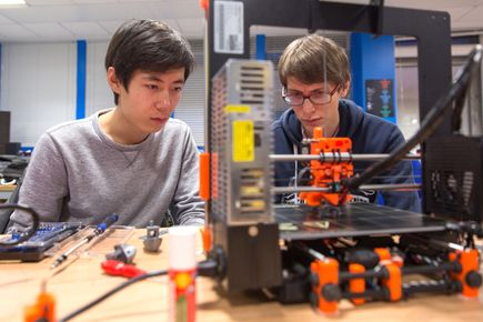 2 students watching a 3d printer in action