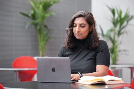 Postgraduate student sitting at desk with laptop