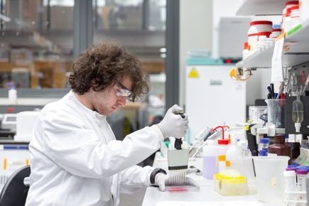 A medicine student uses a pipette in the lab