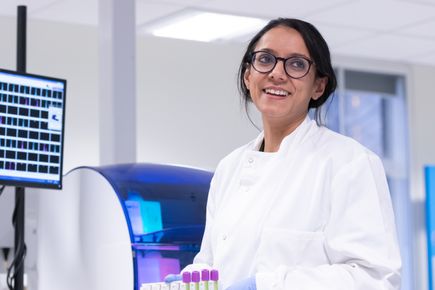 A woman in a lab coat holds a tray of test tubes