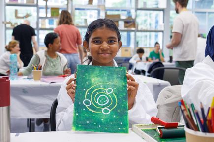 Child shows artwork at a family workshop in The Invention Rooms