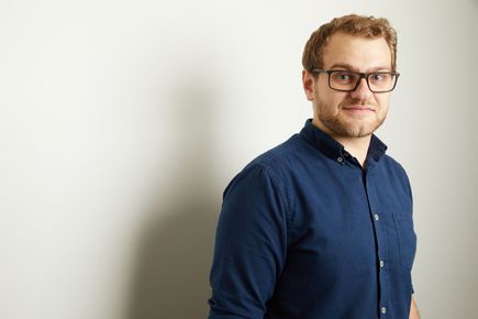 Alex Bond smiles at the camera, against a white background