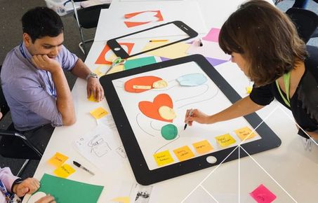 A woman and a man drawing out their idea on a large piece of paper