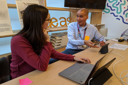 Two people talking together next to a table