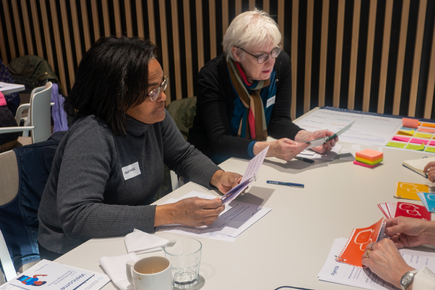 Two women sat next to each other reading a booklet