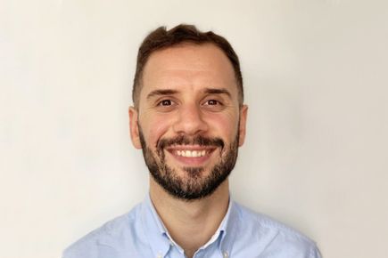 Portrait of Founders' Pledger Manos Halicioglu smiling at camera against a white background