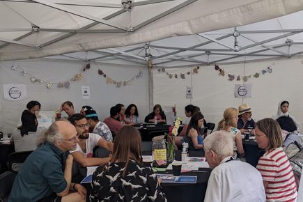 Groups of people sitting at 3 circular tables.