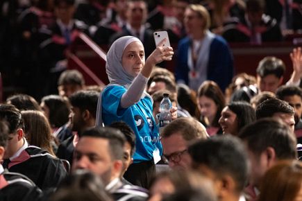 A person holding a phone in a room full of people