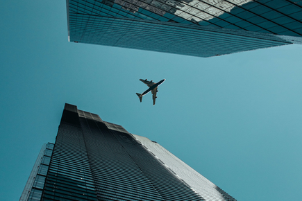 Looking up between two skyscrapers at a plane