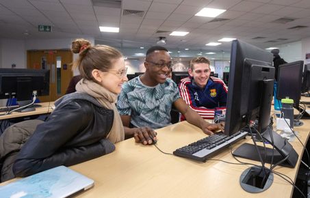 Two men and a woman at a computer desk