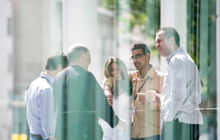 Postgrad students chatting outside the library with coffees