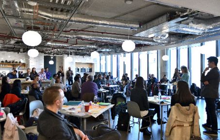 People sat watching a group present at a hackathon