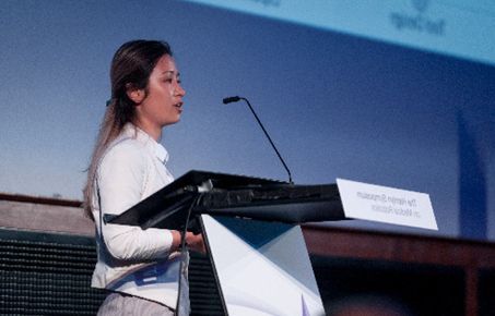 A woman presenting from a lectern