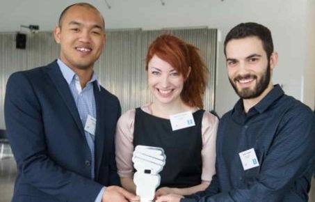 Two men and a woman holding a trophy