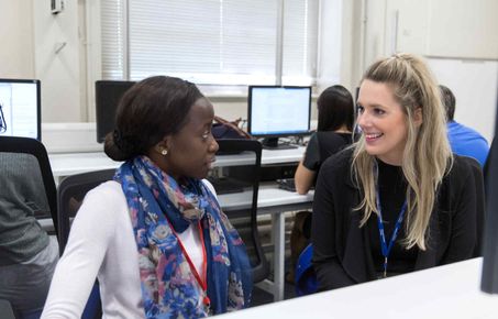 Member of staff discussing work with students during Health Data Analytics course at Imperial College London