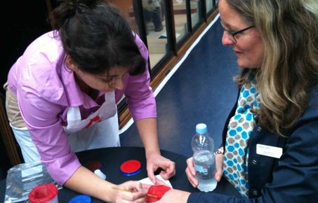 Lady paints heart on person's hand