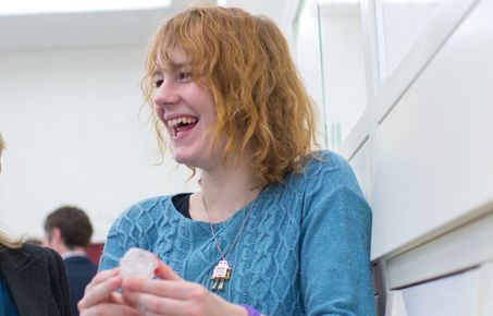 Student smiles while holding a rock.