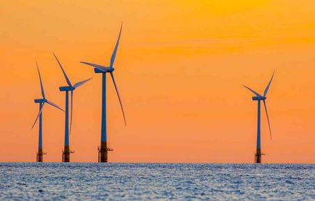 offshore wind turbines against an orange sky