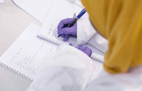 Student writing notes in a laboratory