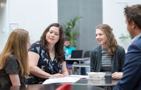 Group of staff sat round a table smiling