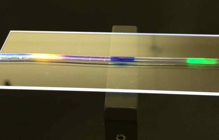 Optical fibre showing different colours on a microscope slide