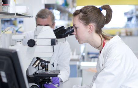 woman looking into microscope in a lab