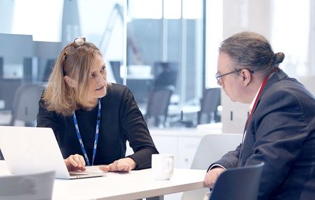 Two people talking over a computer