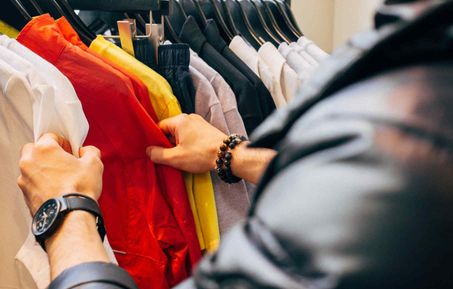 Man looking through a clothing rack. 