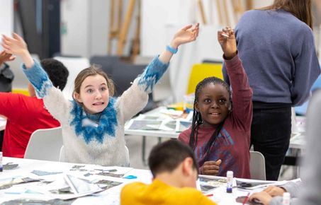 Two students with their hands in the air