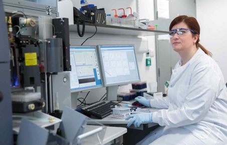 Female researcher sits in front of results on screens